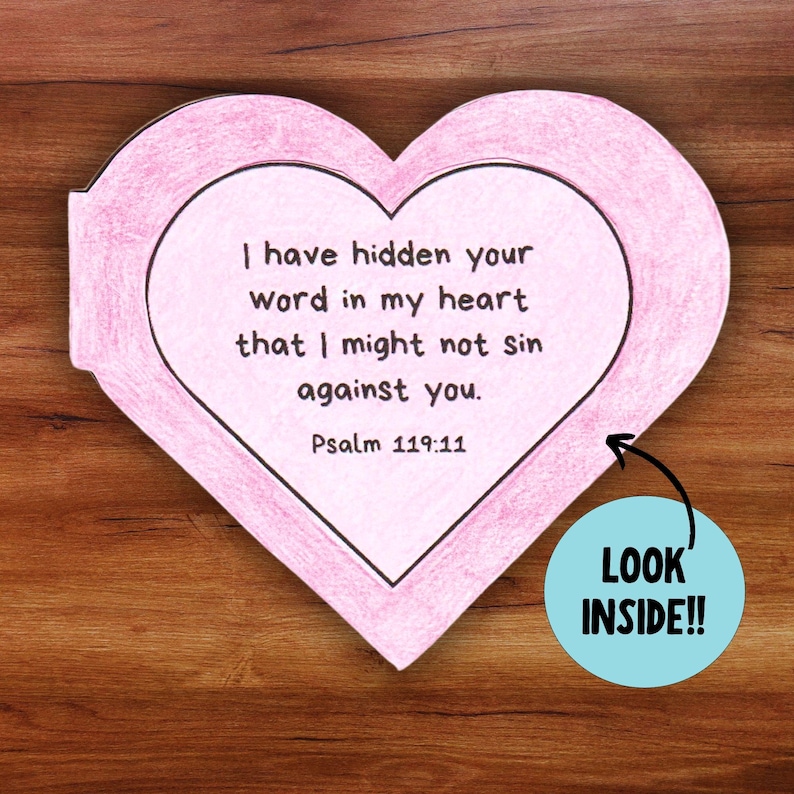 May include: A pink heart-shaped paper craft with a Bible verse inside. The verse reads "I have hidden your word in my heart that I might not sin against you. Psalm 119:11". A blue circle with the text "LOOK INSIDE!!" is on the right side of the image.