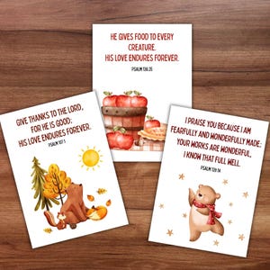 May include: Three white cards with watercolor illustrations and text. One card features a bear, squirrel, fox, and text from Psalm 107:1. Another shows apples and text from Psalm 136:25. The third card has a bear and text from Psalm 139:14.