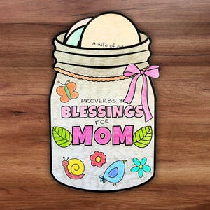 May include: A hand-drawn jar-shaped card with the words "Blessings for Mom" and decorative elements like a butterfly, snail, and flowers. The card has a pink bow and contains several small, round papers.