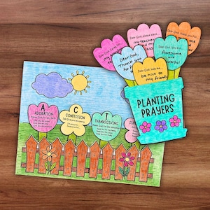 May include: A colorful, handmade craft featuring a garden scene with a fence, flowers, and a sun. The words "Planting Prayers" are on a flower pot. Flower-shaped cards with prayers are included.