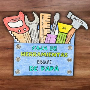 May include: A colorful, handmade paper toolbox with various tool cutouts, including a saw, wrench, ruler, screwdriver, and hammer. The toolbox is blue with the words "CAJA DE HERRAMIENTAS BÍBLICAS DE PAPÁ" in green and yellow. The tools have Spanish words.