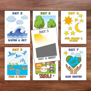 May include: Set of seven illustrated cards depicting the days of creation. Each card features colorful drawings and text, including "Day 1: Day & Night," "Day 2: Water & Sky," and "Day 7: God Rested." The cards are arranged on a wooden surface.