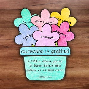 May include: A handmade paper flower arrangement in a green pot, with the words "Cultivating Gratitude." Each flower is a different color and has a word written on it. The pot has a Bible verse written on it.