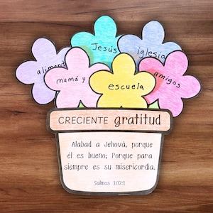 Puede incluir: Un colorido ramo de flores de papel con las palabras "aliment", "mamá y", "Jesús", "iglesia", "escuela" y "amigos" escritas en los pétalos. La maceta dice "CRECIENTE gratitud" y un versículo bíblico. Sobre una superficie de madera.