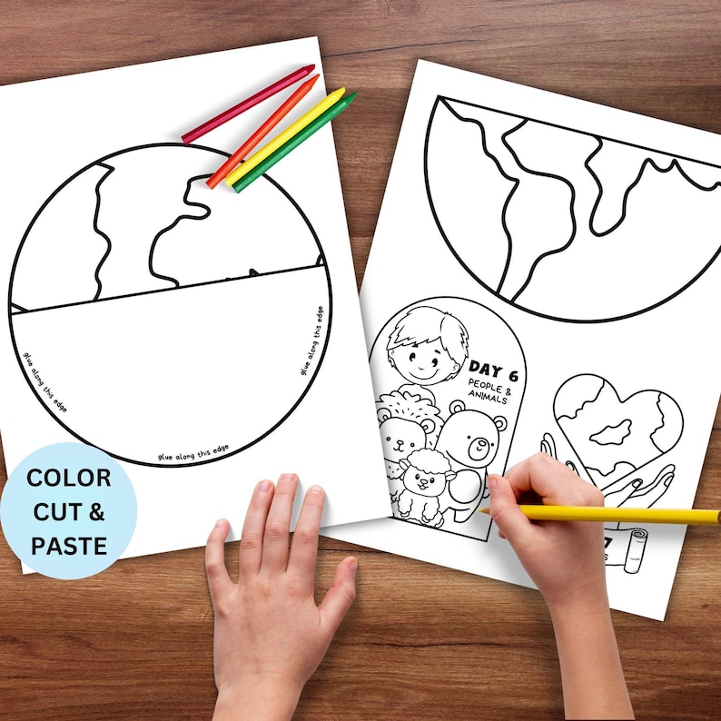 May include: Two white coloring pages with outlines of the Earth and illustrations of people and animals. The text "COLOR CUT & PASTE" is on one page. Crayons in red, yellow, and green are on the table. A hand is holding a yellow pencil.