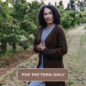 May include: A brown crochet cardigan with a long, open front and long sleeves. The cardigan is shown on a person standing in a cherry orchard. The text "PDF PATTERN ONLY" is displayed on a brown rectangle.