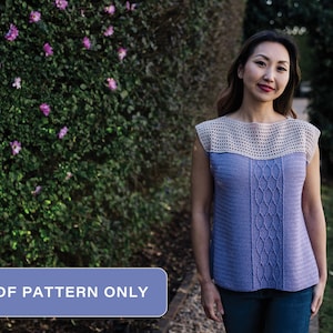 May include: A crochet top with a cable stitch pattern in a light purple color. The top has a beige crochet trim around the neckline and armholes. The top is sleeveless and has a relaxed fit.