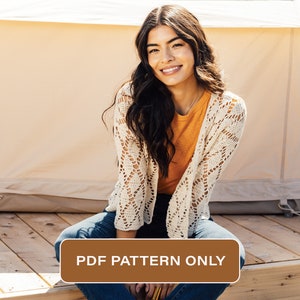 May include: A woman wearing a white crochet cardigan over a burnt orange t-shirt and blue jeans sits on a wooden deck in front of a beige tent. The text "PDF PATTERN ONLY" is on a brown rectangle.