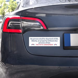 Può includere: Un adesivo bianco sul paraurti di un'auto con il testo "Nessuno sarà privato della vita, della libertà o della proprietà senza un giusto processo. IL QUINTO EMENDAMENTO" in testo blu e rosso.