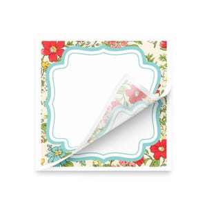 May include: A square notepad with a floral design and a light blue border. The notepad has a white, scalloped frame for writing. The corner of the top sheet is peeled back, revealing the floral pattern on the underside.