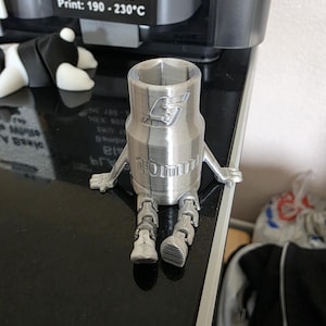 Può includere: Una statuetta a forma di bussola da 10 mm color argento con braccia e gambe articolate. Il corpo cilindrico presenta il logo Snap-on in rilievo e la scritta 10 mm. La figura è progettata con una parte superiore esagonale cava.