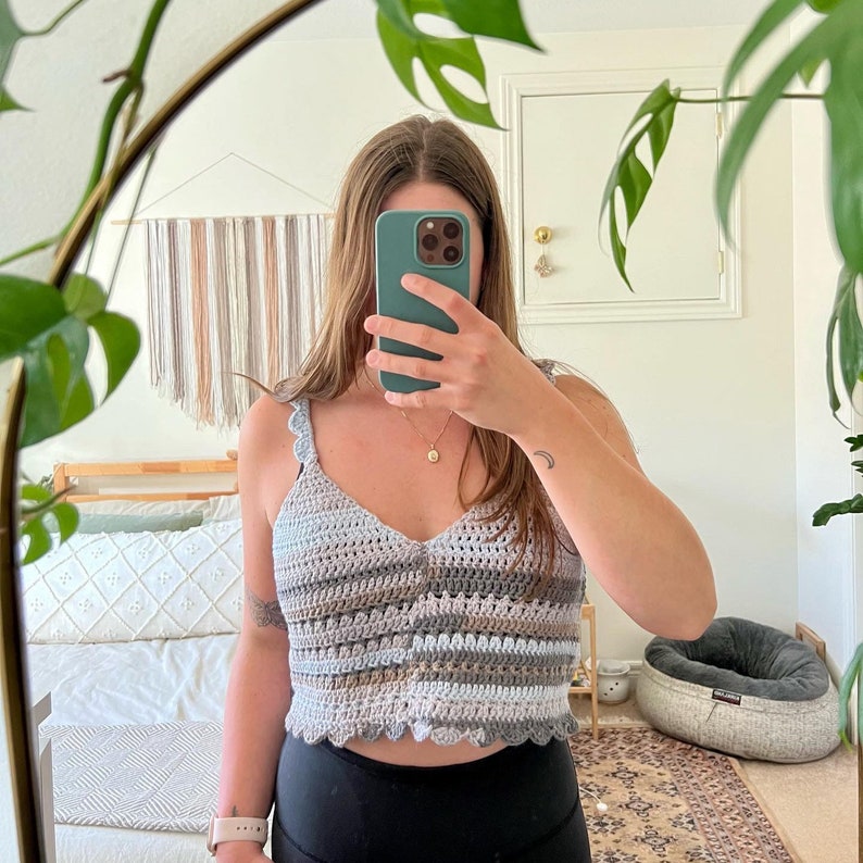 May include: A crocheted tank top with a scalloped hem in shades of blue, brown, and white. The top is sleeveless and has a V-neck.