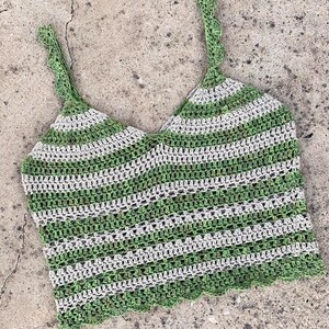 May include: Green and white striped crochet top with a scalloped edge. The top has thin straps and a cropped length.