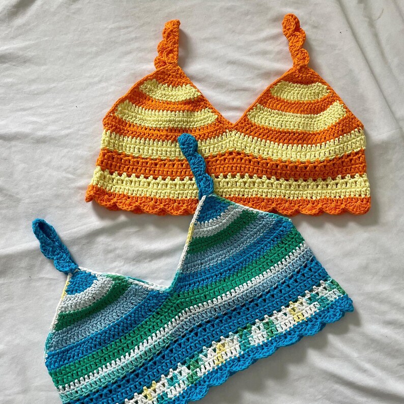 May include: Two crocheted tops, one with orange, yellow, and white stripes and the other with blue, green, and white stripes.