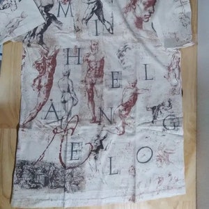 May include: A white t-shirt with a print of anatomical drawings and the word "Melencolia" in a stylized font.