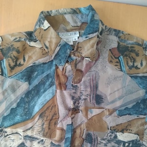 Puede incluir: Una camisa de estampado marrón, azul y beige con cuello y cierre de botones. La camisa tiene un bolsillo en el lado izquierdo y la etiqueta "seta by tineli" en el cuello. La etiqueta de talla dice "S".