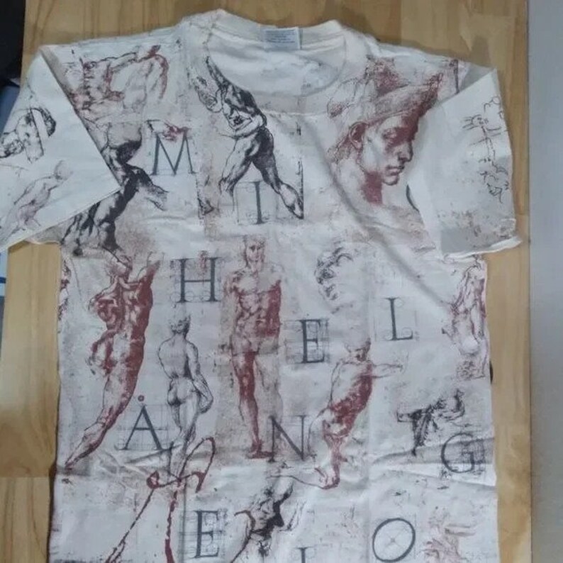 May include: A white t-shirt with a print of various sketches of human figures and the words "Michelangelo" in a vintage style.