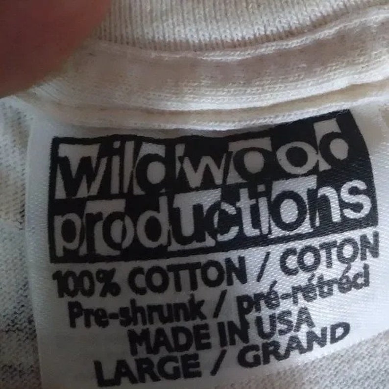 May include: White tag with black text that reads "Wildwood Productions 100% Cotton/Coton Pre-shrunk/pr&eacute;-r&eacute;tr&eacute;ci MADE IN USA LARGE/GRAND"
