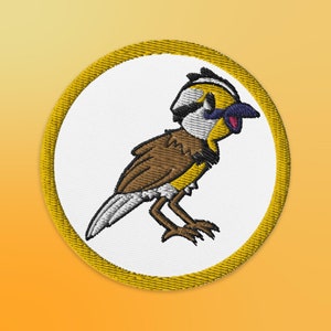 May include: A yellow and white embroidered patch with a cartoon bird with brown and white feathers and a yellow beak. The bird is singing with its mouth open.