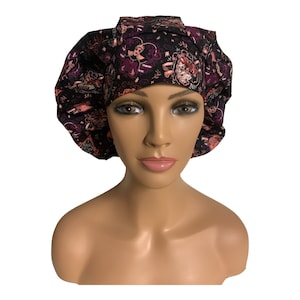 May include: A black scrub cap with a pink and gold floral pattern. The cap has a gathered top and a tie at the back.
