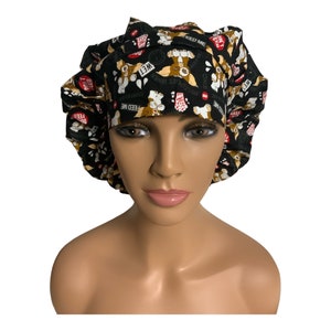 May include: Black scrub hat with a repeating pattern of cartoon dogs wearing hats and saying "Feed Me" and "Wet".