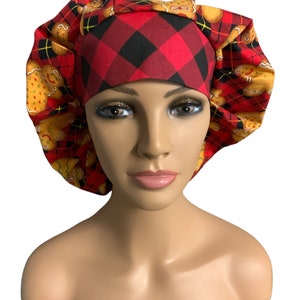 May include: Red and black plaid scrub hat with a gingerbread cookie print. The hat has a tie on the back.