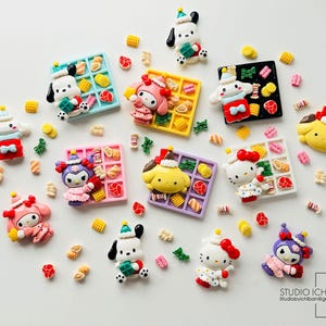 Può includere: Assortimento di ciondoli in pasta polimerica colorati e fatti a mano che rappresentano personaggi dei cartoni animati popolari. I ciondoli sono decorati con dettagli come fiocchi, cuori e stelle. I ciondoli sono esposti su uno sfondo bianco.