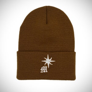 May include: A brown knitted beanie with a white embroidered star and the letters "MH" in a gothic font.