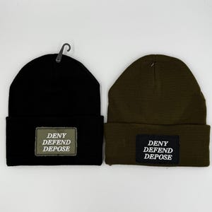 May include: Two knit beanies, one black and one olive green, with a black patch on each that reads "DENY DEFEND DEPOSE" in white text.