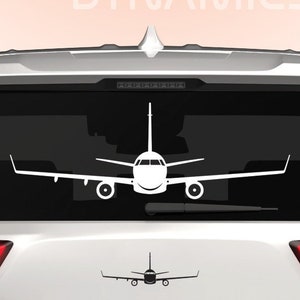 May include: White silhouette of an airplane on the back window of a white SUV. The SUV has a license plate that reads "DINGO".