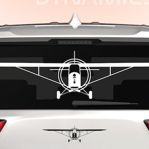 Puede incluir: Silueta blanca de un avión pequeño sobre fondo negro. El avión está en la ventana trasera de un SUV blanco. El SUV tiene un logotipo de Dingo Dynamics en la parte trasera.