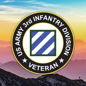 May include: Circular emblem featuring the text "US ARMY 3rd INFANTRY DIVISION VETERAN" in white lettering on a black ring. The center displays a square with blue and white diagonal stripes, framed by a green border. The background shows a mountain range.