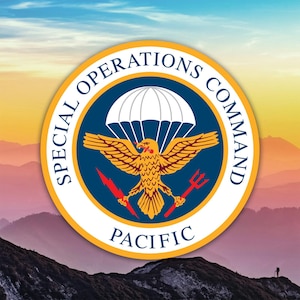 May include: A circular emblem with the text "SPECIAL OPERATIONS COMMAND PACIFIC" in white lettering. The emblem features a parachute, an eagle holding a trident and a lightning bolt, set against a blue background with a yellow border.