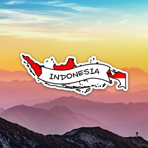 Puede incluir: Una pegatina con el contorno de Indonesia en rojo y blanco, con la palabra "INDONESIA" en una pancarta. La pegatina está colocada sobre un fondo de una cordillera y un cielo colorido.