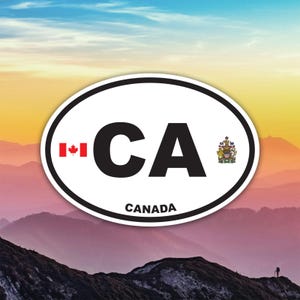 Peut inclure: Autocollant ovale blanc avec les lettres "CA" en noir, le drapeau canadien et le mot "CANADA" en noir. L'autocollant a une bordure noire et un blason sur le côté droit. L'arrière-plan montre une chaîne de montagnes.
