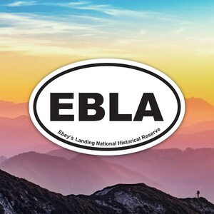 Puede incluir: Pegatina ovalada con las letras EBLA en negrita negra, con el texto "Ebey's Landing National Historical Reserve" debajo. La pegatina está colocada sobre un fondo de una cordillera y un cielo colorido.