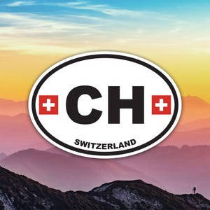 Peut inclure: Autocollant ovale avec bordure blanche. Il présente les lettres "CH" en noir, avec des croix suisses rouges de chaque côté. Le mot "SWITZERLAND" est imprimé en dessous. Le fond montre une chaîne de montagnes.
