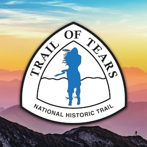 May include: A white and black emblem with the text "TRAIL OF TEARS" and "NATIONAL HISTORIC TRAIL" encircling a blue silhouette of a person. The background features a mountain range under a colorful sky.