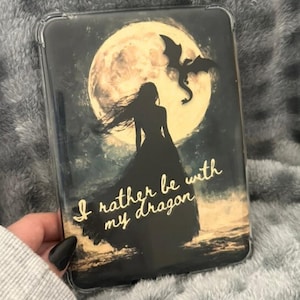 May include: A black phone case featuring a silhouette of a woman in a long dress, a dragon, and a full moon. The text "I rather be with my dragon" is written in gold script.
