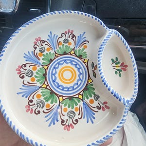 Könnte beinhalten: Weißes Keramik-Serviertablett mit einem zentralen Blumendesign in Blau, Grün, Gelb und Rosa. Das Tablett hat ein separates Fach und einen blau gestreiften Rand, ideal für Snacks oder Vorspeisen.