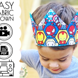 May include: A child wearing a blue shirt and a fabric crown with a superhero theme. The crown is made of blue fabric with a white border and features a variety of superhero characters, including Spiderman, Iron Man, and Captain America. The crown is decorated with yellow hexagons.