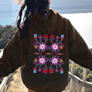 May include: A brown hoodie with a floral embroidery design on the back. The embroidery features pink, red, blue, and yellow flowers.