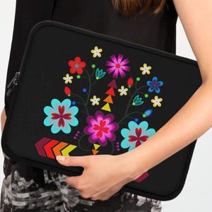 May include: Black laptop sleeve featuring a colourful floral design with a variety of flowers, leaves, and geometric shapes. The design is centred on the sleeve and is surrounded by a black background.