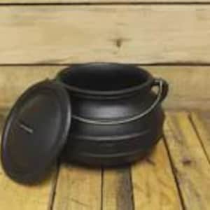 May include: A matte black cast iron cauldron with a rounded body, a wide opening, and a matching circular lid resting beside it. The pot features a sturdy metal handle attached to the sides, designed for carrying or hanging, with a smooth finish.