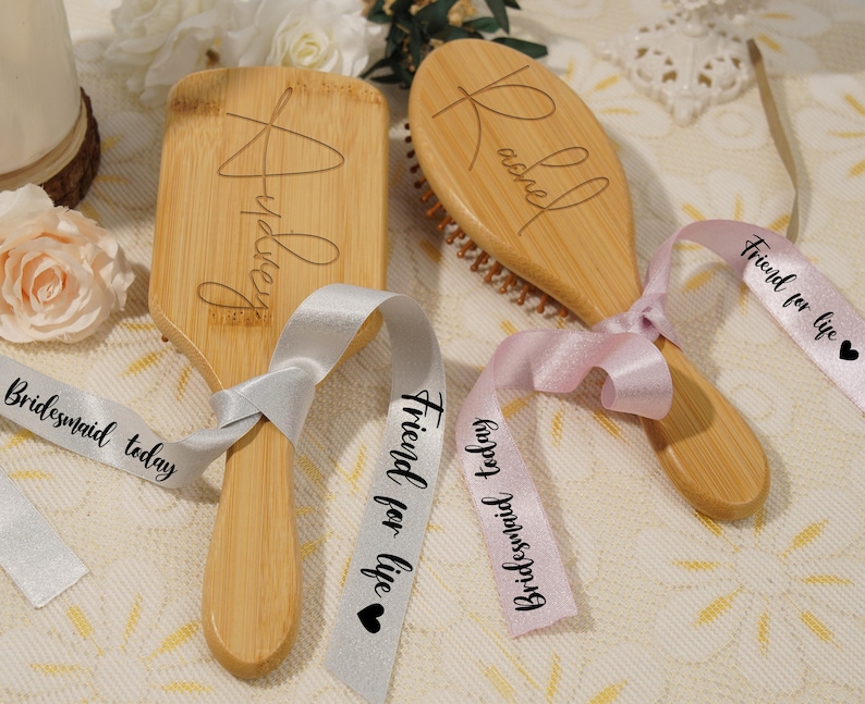May include: Two wooden hairbrushes with engraved names, tied with ribbons. One brush is rectangular with "Audrey" engraved, the other is oval with "Rachel". Ribbons say "Friend for life" and "Bridesmaid today".