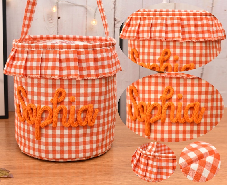 May include: A cylindrical fabric basket featuring an orange and white gingham pattern. The basket has a ruffled top edge and a handle. The name Sophia is embroidered in orange yarn on the front. Circular insets show the ruffle and fabric detail.