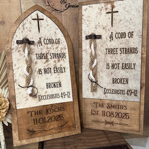 May include: Two wooden wall signs featuring a cowhide background, a cross, and a braided rope. The text reads A CORD OF THREE STRANDS IS NOT EASILY BROKEN ECCLESIASTES 4:9-12. One sign is arched, the other rectangular, both personalized with names and dates.
