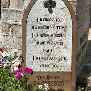 May include: A rustic wooden sign with a white cowhide background. The sign features a romantic message about choosing someone in every lifetime and world. The sign is personalized with the text "The Boldts Est. 08.30.2025".