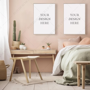 May include: Two framed posters with the text "Your Design Here" hanging on a light pink wall above a bed with a light green linen duvet and a wooden bench at the foot of the bed.