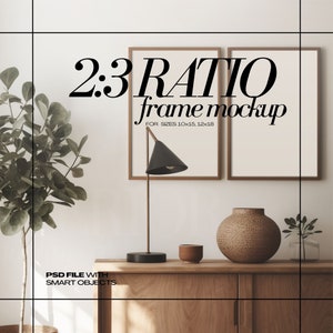 Puede incluir: Dos marcos de fotos de madera marrón con fondo blanco y borde dorado. Los marcos están colgados en una pared blanca. El texto "2:3 RATIO frame mockup FOR SIZES 10x15, 12x18" está impreso en negro en la pared. Una mesa de madera marrón con una lámpara, un jarrón y una taza está en primer plano.